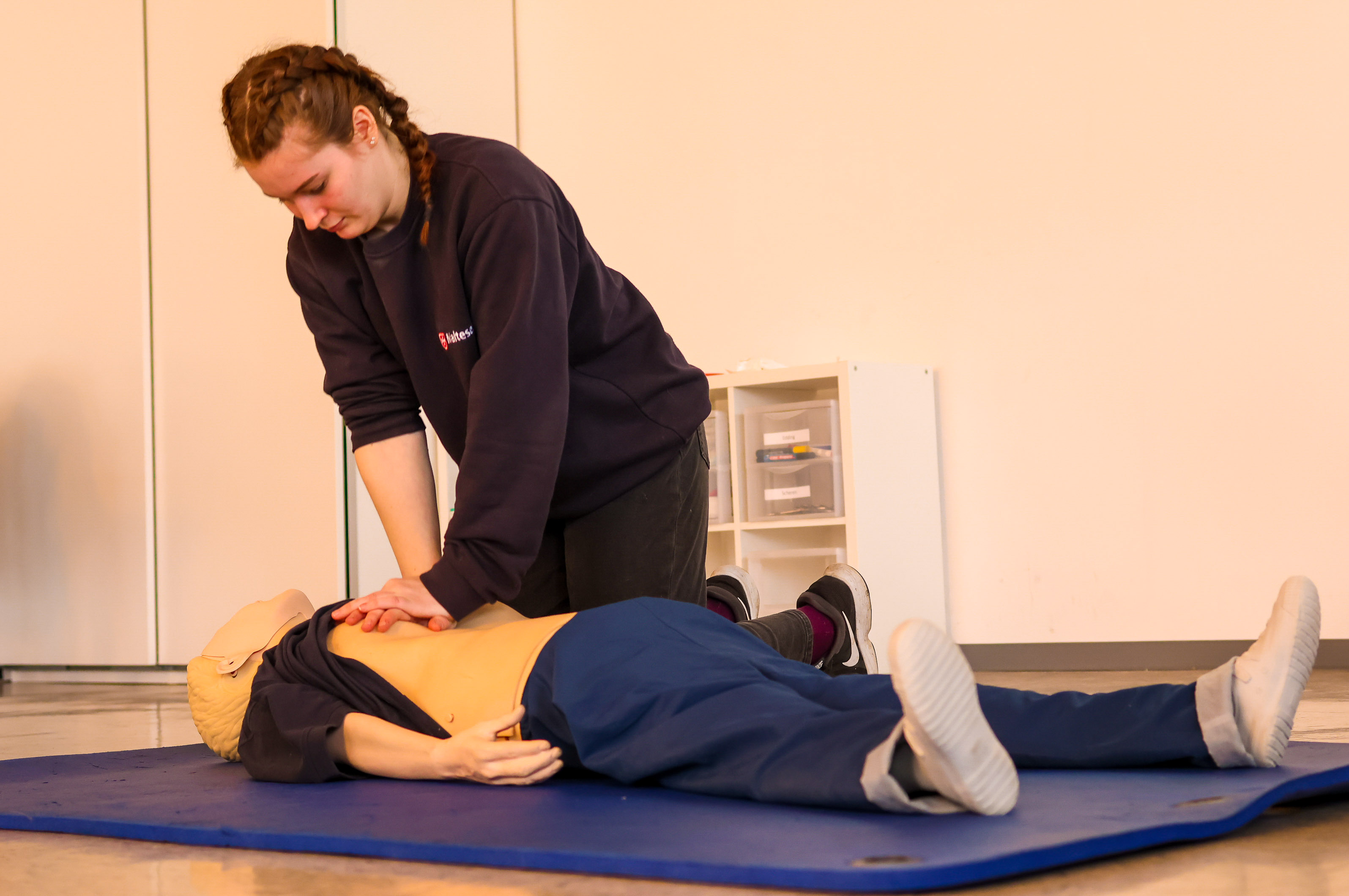 Erste-Hilfe-Ausbilderin demonstriert die Technik der Herzdruckmassage an einer Übungspuppe.