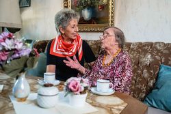 Zwei Frauen unterhalten sich bei Kaffee und Kuchen.